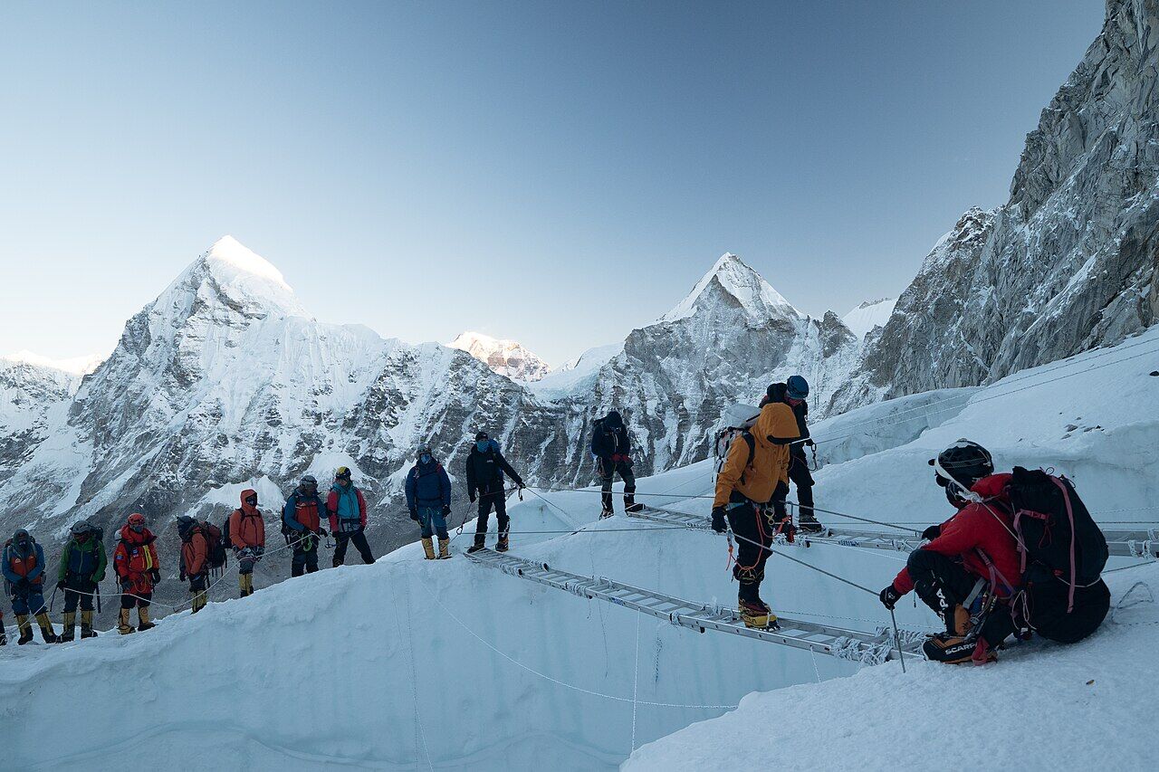 A rope team crossing ladders in the Khumbu Icefall